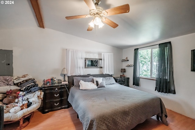 bedroom featuring vaulted ceiling with beams, light wood-type flooring, and electric panel