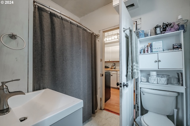 bathroom featuring a sink, toilet, and decorative backsplash