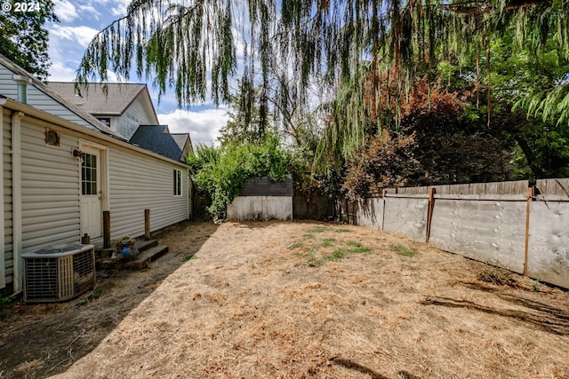 view of yard featuring an outbuilding, a shed, a fenced backyard, and cooling unit