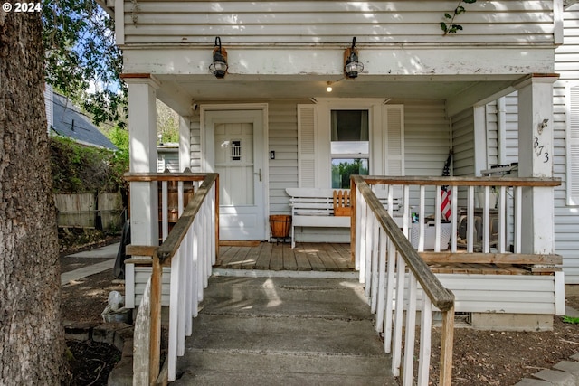 doorway to property featuring a porch and fence