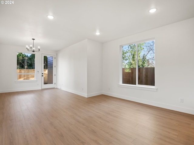 unfurnished room featuring a healthy amount of sunlight, light hardwood / wood-style flooring, and a notable chandelier