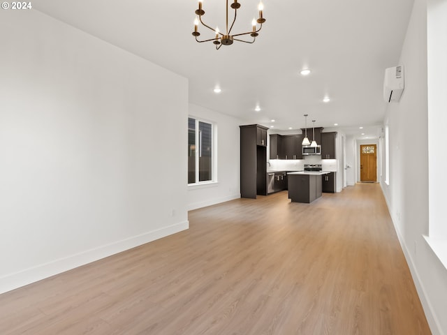 unfurnished living room with light wood-type flooring, a notable chandelier, and a wall mounted air conditioner