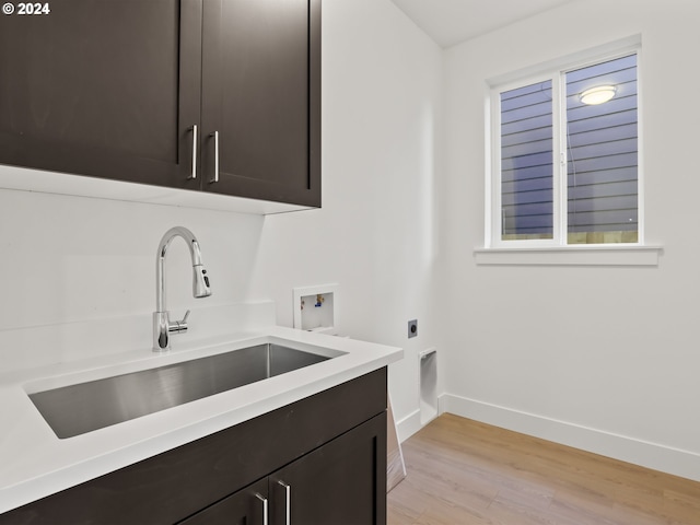 clothes washing area with cabinets, light hardwood / wood-style floors, sink, washer hookup, and hookup for an electric dryer