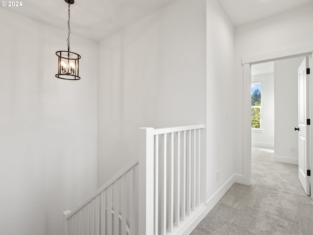 hall featuring light colored carpet and a notable chandelier