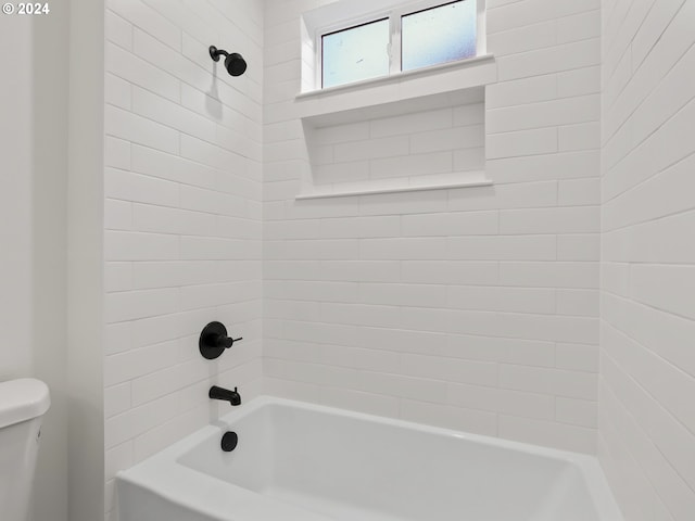 bathroom featuring toilet and tiled shower / bath combo