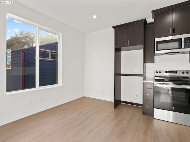 kitchen with dark brown cabinetry, light wood-type flooring, appliances with stainless steel finishes, and backsplash