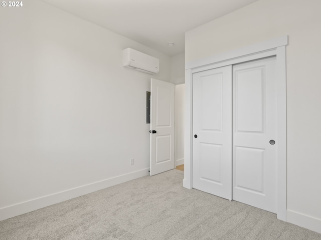 unfurnished bedroom with a wall mounted AC, light colored carpet, and a closet