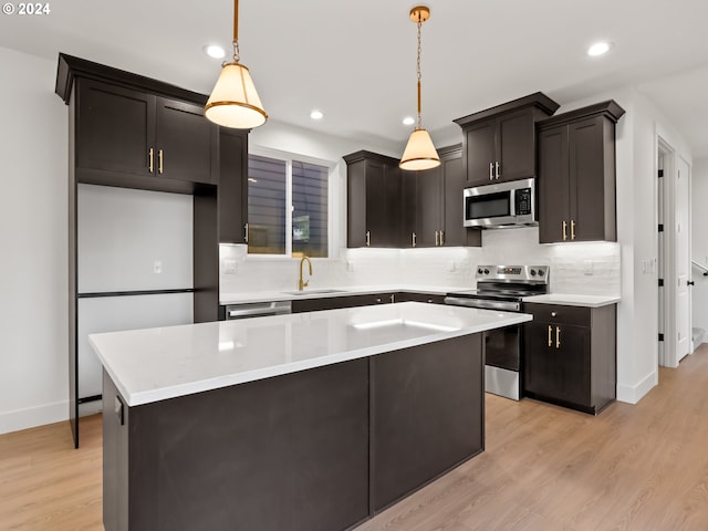 kitchen with decorative backsplash, decorative light fixtures, appliances with stainless steel finishes, and light hardwood / wood-style flooring