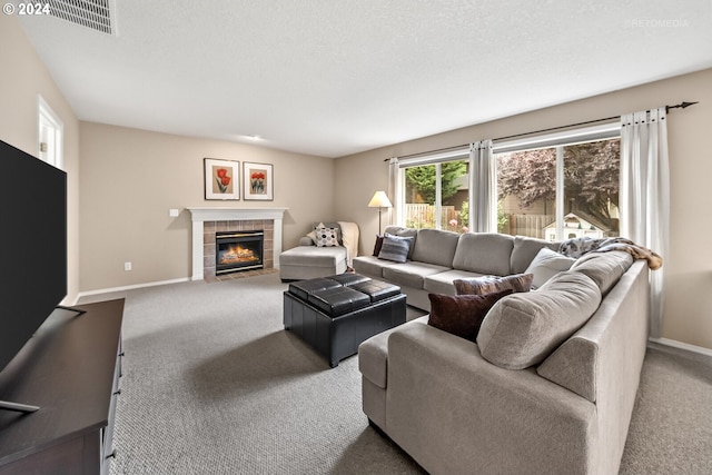 carpeted living room with a textured ceiling and a tile fireplace