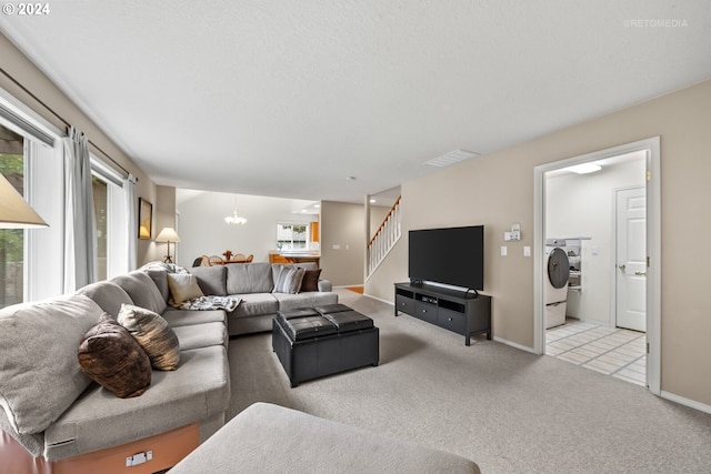 carpeted living room with an inviting chandelier and washing machine and dryer