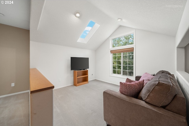 carpeted living room featuring vaulted ceiling with skylight and a textured ceiling