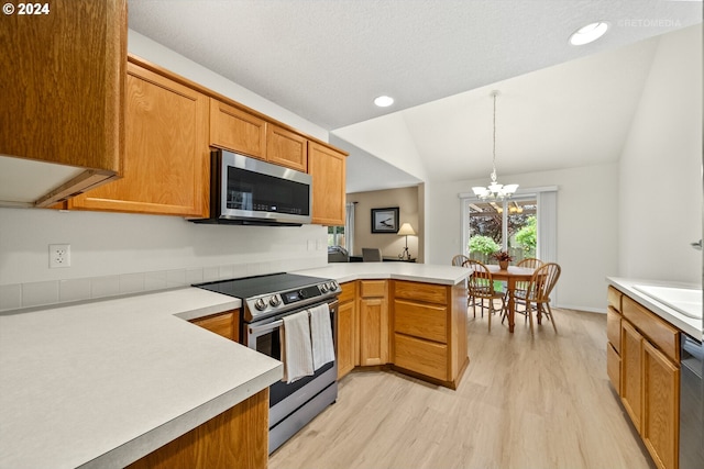 kitchen featuring a chandelier, lofted ceiling, kitchen peninsula, stainless steel appliances, and decorative light fixtures