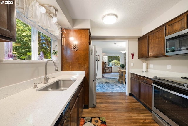 kitchen featuring a textured ceiling, sink, stainless steel appliances, and dark hardwood / wood-style flooring