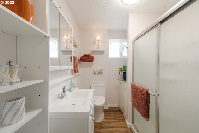 bathroom with walk in shower, hardwood / wood-style flooring, vanity, and toilet