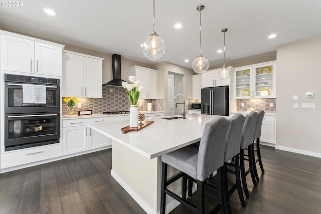 kitchen featuring light countertops, white cabinets, a sink, an island with sink, and black appliances