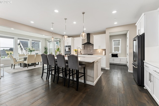 kitchen featuring white cabinets, high quality fridge, light countertops, and hanging light fixtures