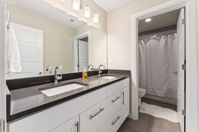 full bath featuring double vanity, tile patterned flooring, a sink, and toilet