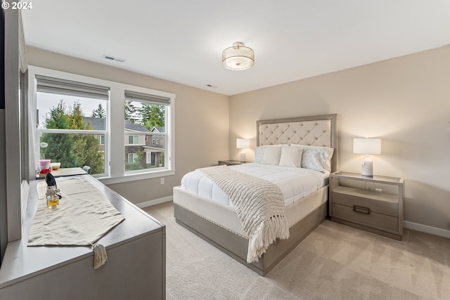 bedroom featuring visible vents, light carpet, and baseboards