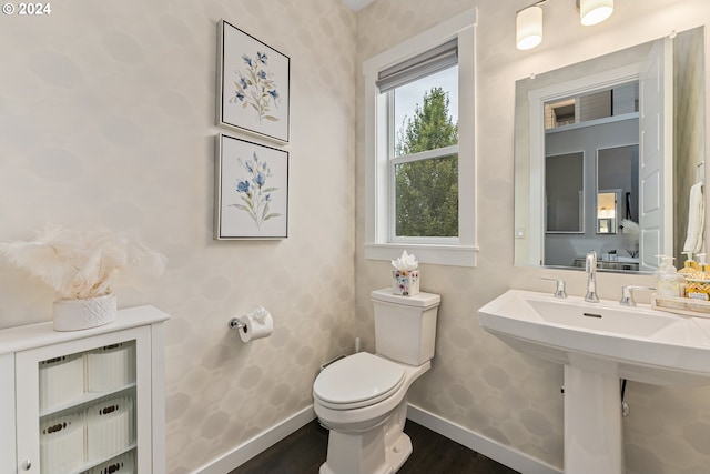 half bathroom featuring baseboards, a sink, toilet, and wood finished floors