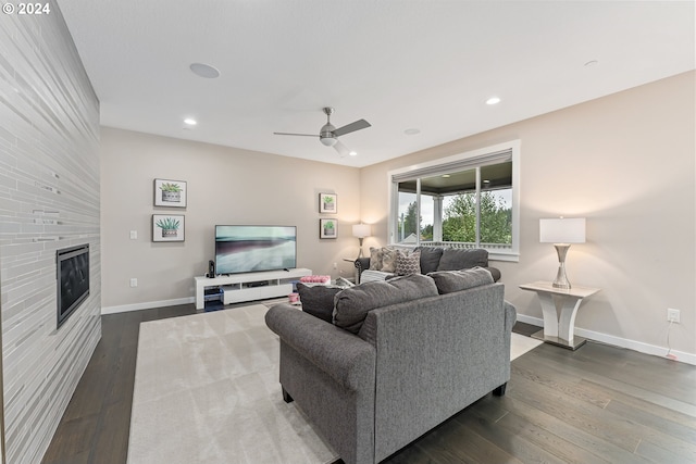 living room featuring recessed lighting, a large fireplace, baseboards, and dark wood-style flooring