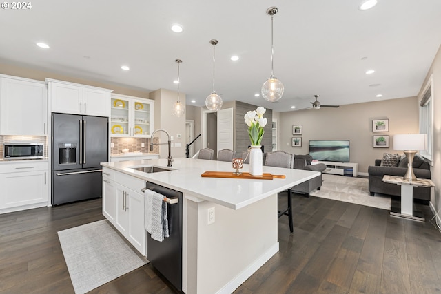 kitchen featuring stainless steel appliances, a sink, white cabinetry, light countertops, and an island with sink