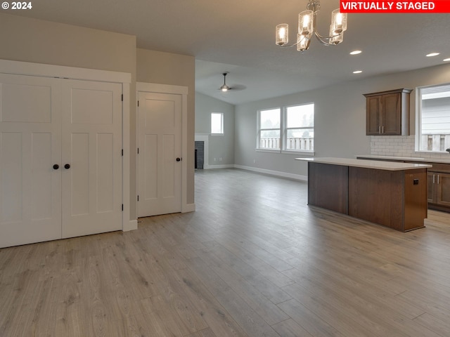 kitchen featuring a center island, decorative backsplash, light hardwood / wood-style floors, and ceiling fan with notable chandelier