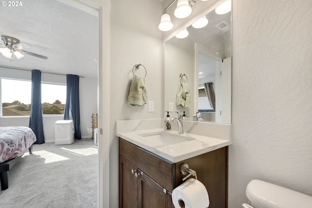 bathroom featuring vanity, ceiling fan, toilet, and a textured ceiling