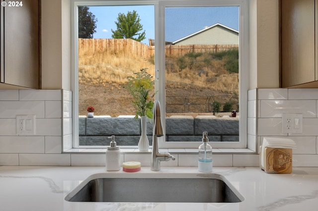 interior details with light stone countertops, sink, and tasteful backsplash