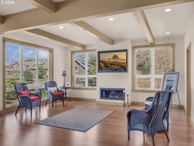 living area featuring beamed ceiling, plenty of natural light, and light wood-type flooring