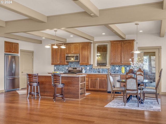 kitchen featuring hanging light fixtures, beam ceiling, a center island, and stainless steel appliances