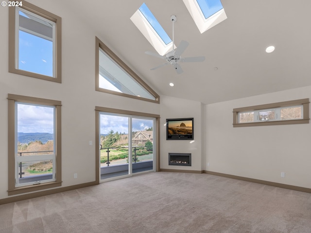 32227 Seascape Ln, Cannon Beach, OR 97110 - unfurnished living room featuring a skylight, a glass covered fireplace, carpet flooring, high vaulted ceiling, and baseboards