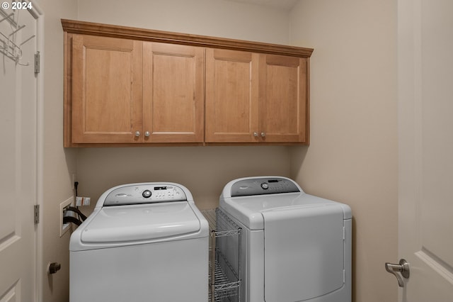 laundry area with washing machine and clothes dryer and cabinets