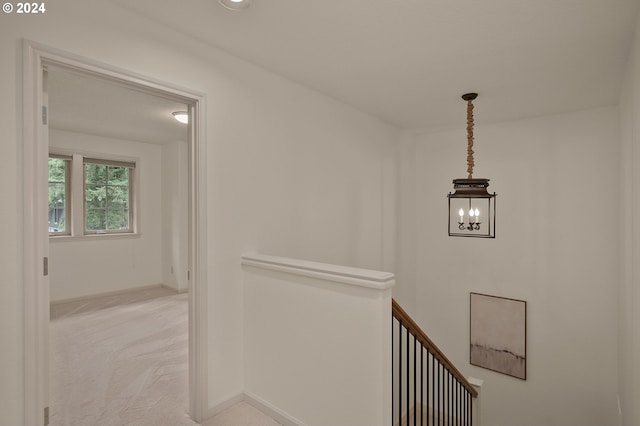 hallway with light carpet and an inviting chandelier