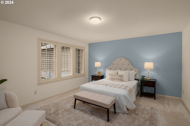 bedroom with a textured ceiling and light colored carpet