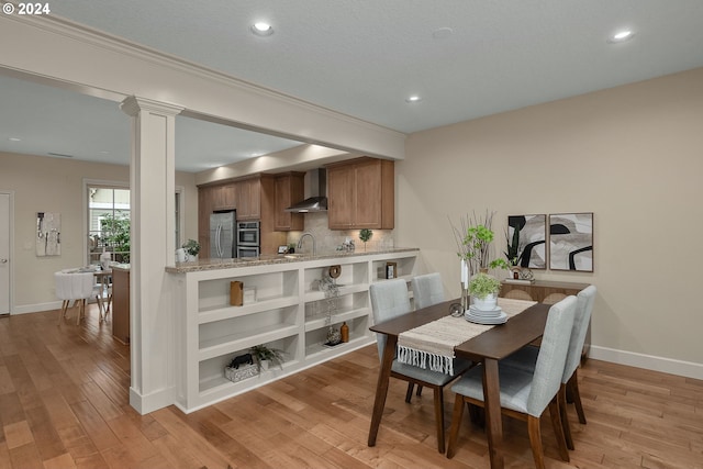 dining room with light hardwood / wood-style floors, decorative columns, and sink