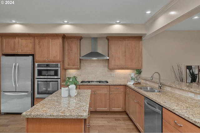 kitchen featuring light stone countertops, wall chimney range hood, appliances with stainless steel finishes, and sink