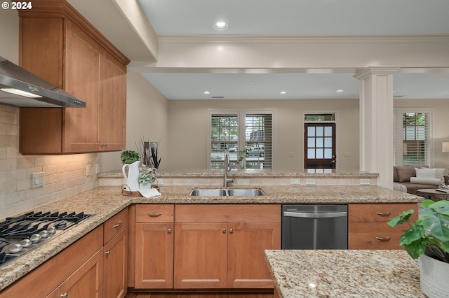 kitchen featuring wall chimney range hood, plenty of natural light, sink, and tasteful backsplash