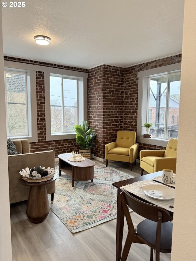 sitting room featuring hardwood / wood-style floors, a textured ceiling, and brick wall