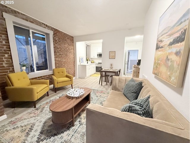 living room with sink, light hardwood / wood-style floors, and brick wall