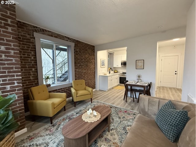 living room featuring sink, brick wall, and light hardwood / wood-style floors