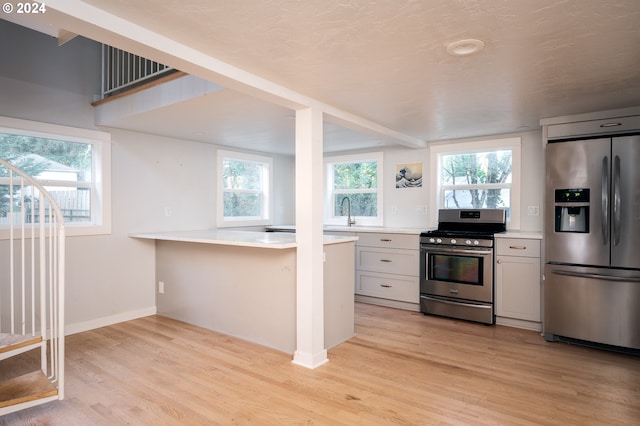 kitchen featuring plenty of natural light, white cabinetry, light hardwood / wood-style floors, and stainless steel appliances