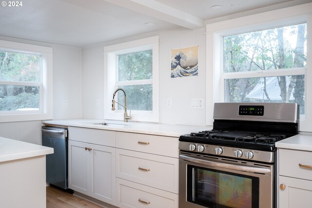 kitchen featuring white cabinetry, appliances with stainless steel finishes, sink, and light hardwood / wood-style flooring