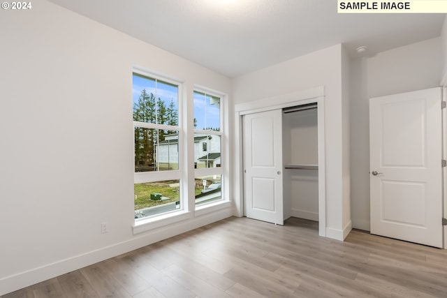 unfurnished bedroom featuring a closet, light hardwood / wood-style floors, and multiple windows