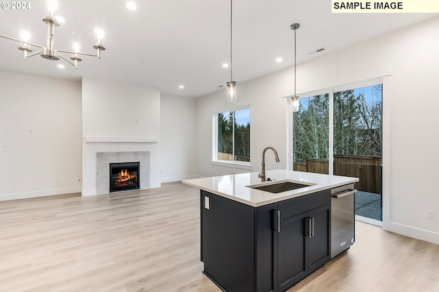 kitchen featuring sink, light hardwood / wood-style flooring, pendant lighting, a fireplace, and a center island with sink