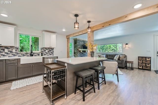 kitchen with white cabinets, decorative light fixtures, light hardwood / wood-style floors, and sink