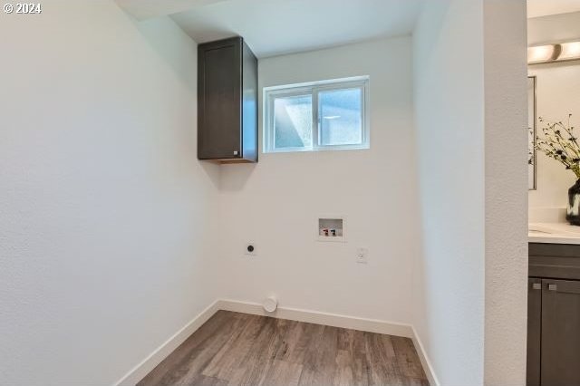 washroom with electric dryer hookup, hookup for a washing machine, cabinets, and hardwood / wood-style flooring