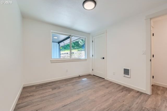 empty room featuring light hardwood / wood-style floors and heating unit