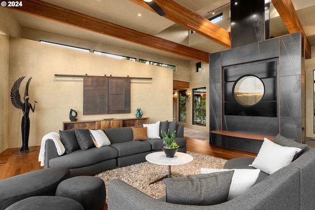 living room featuring beam ceiling, a barn door, wood-type flooring, and track lighting