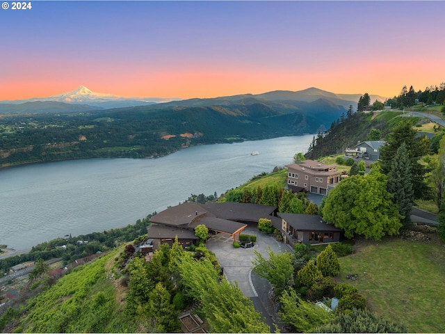 aerial view at dusk featuring a water and mountain view