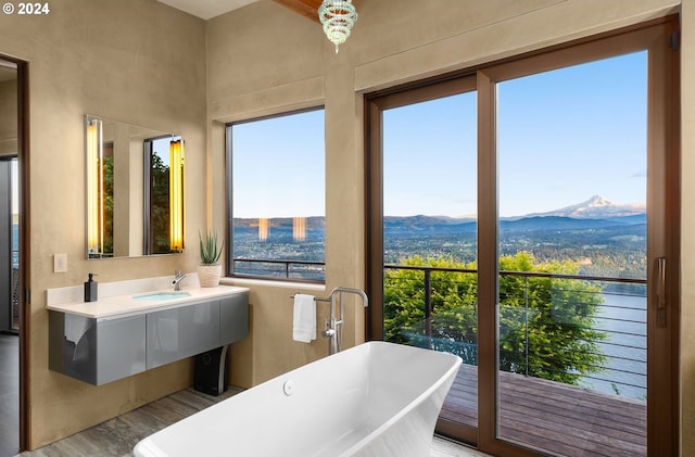 bathroom with a mountain view, wood-type flooring, vanity, and a tub